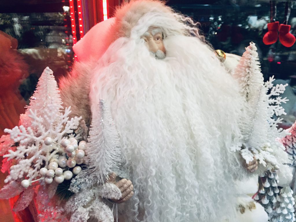 Father christmas with white pendelton coat and white beard, holding white christmas trees and snowflakes